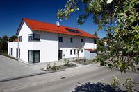 Au&szlig;enansicht der WG in Dewangen. Zu sehen ist ein zweist&ouml;ckiger Neubau in wei&szlig; mit rotem Dach vor blauen Himmel. Im Vordergrund der Anschnitt eines Apfelbaumes.